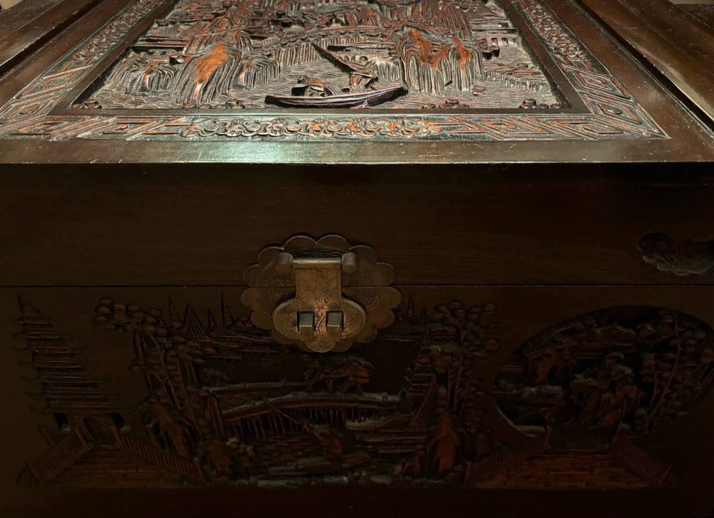 A large Chinese camphor-wood chest, carved with scenes of trees, villages and boats. 