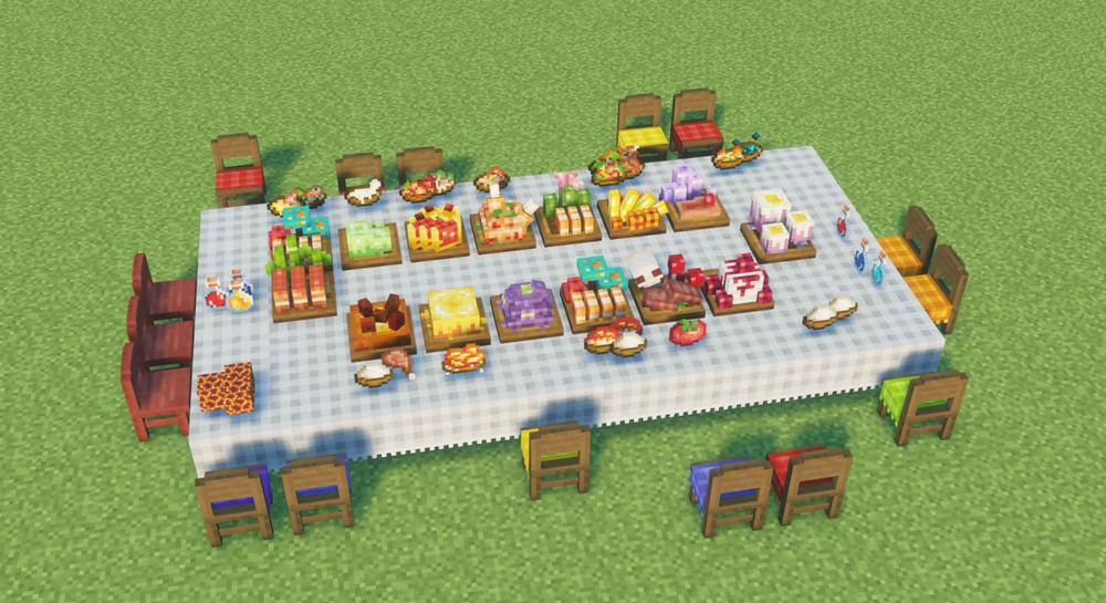 Large table in a grass field surrounded by chairs. The table is covered in different plates with food, drinks, and snacks.