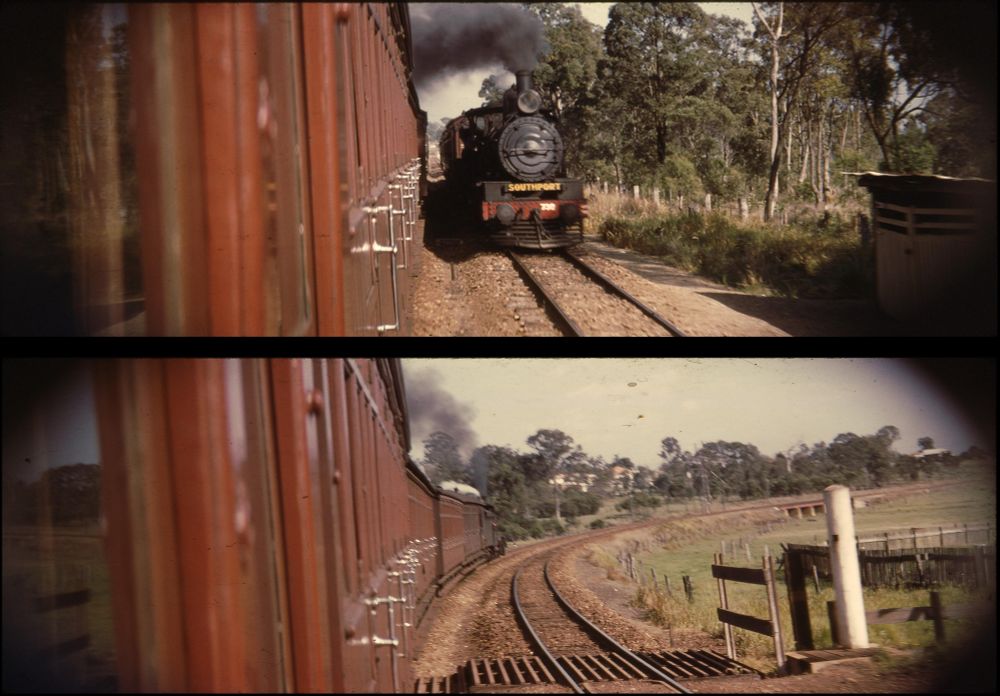 A pair of widescreen colour slides, both taken, inadvisedly, from the open door of a moving railway carriage. The top photo looks towards an approaching steam locomotive, bearing a destination sign reading Southport, the then nearest railway station to Surfers Paradise, travelling through typical eastern Australian bushland. A railway works shed passes by at right, while a level crossing can just be made out in the distance between the two trains. The bottom photo looks from another level crossing, with grids to stop livestock wandering along the tracks, towards a curved culvert over Bulimba Creek and signs of what was then the outskirts of suburban Meanjin Brisbane 