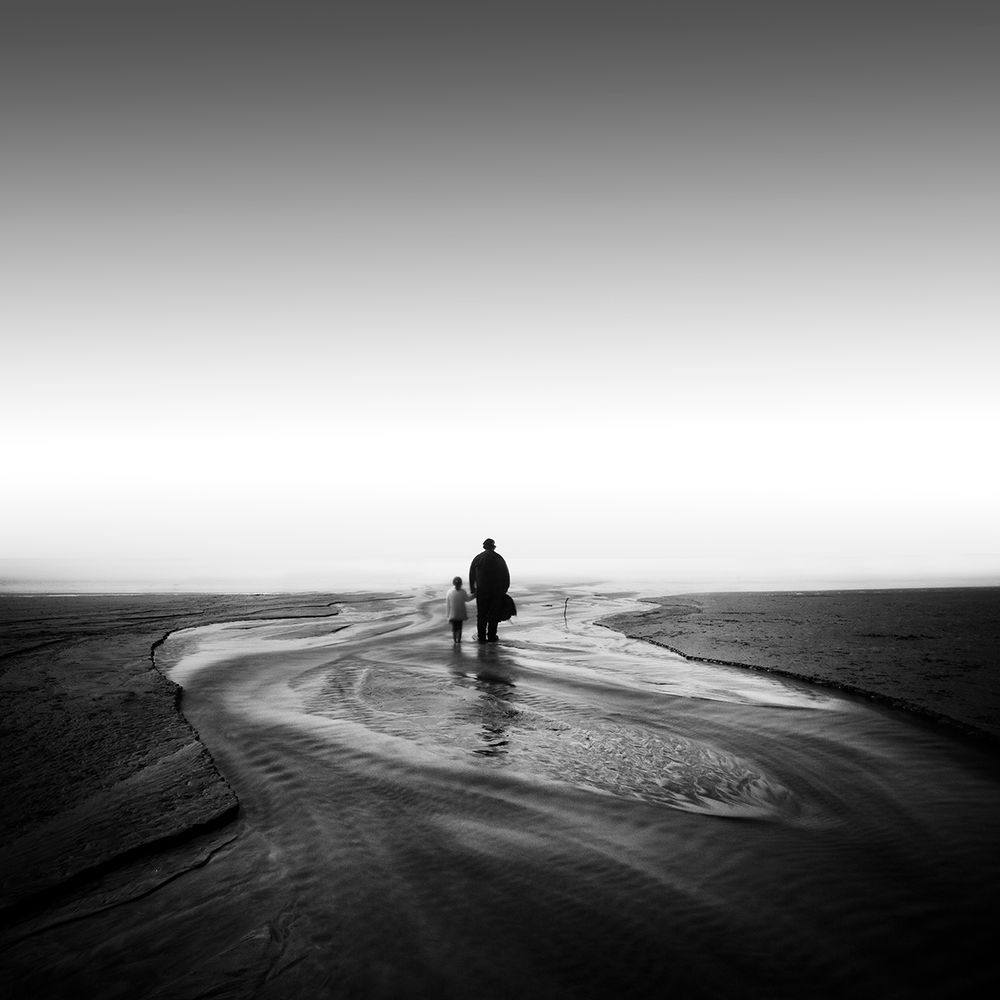 This is a very simple image of a father and daughter standing in water flowing to the sea.