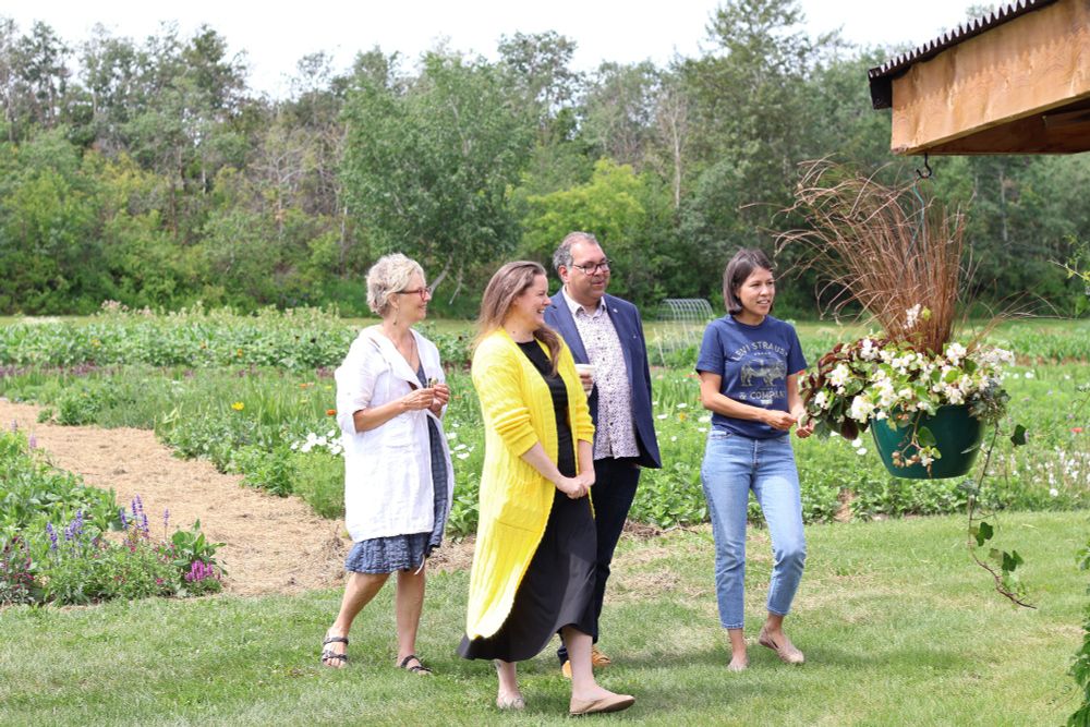 Photo of MLA Sweet, Leader Nenshi and constituents walking in the garden.