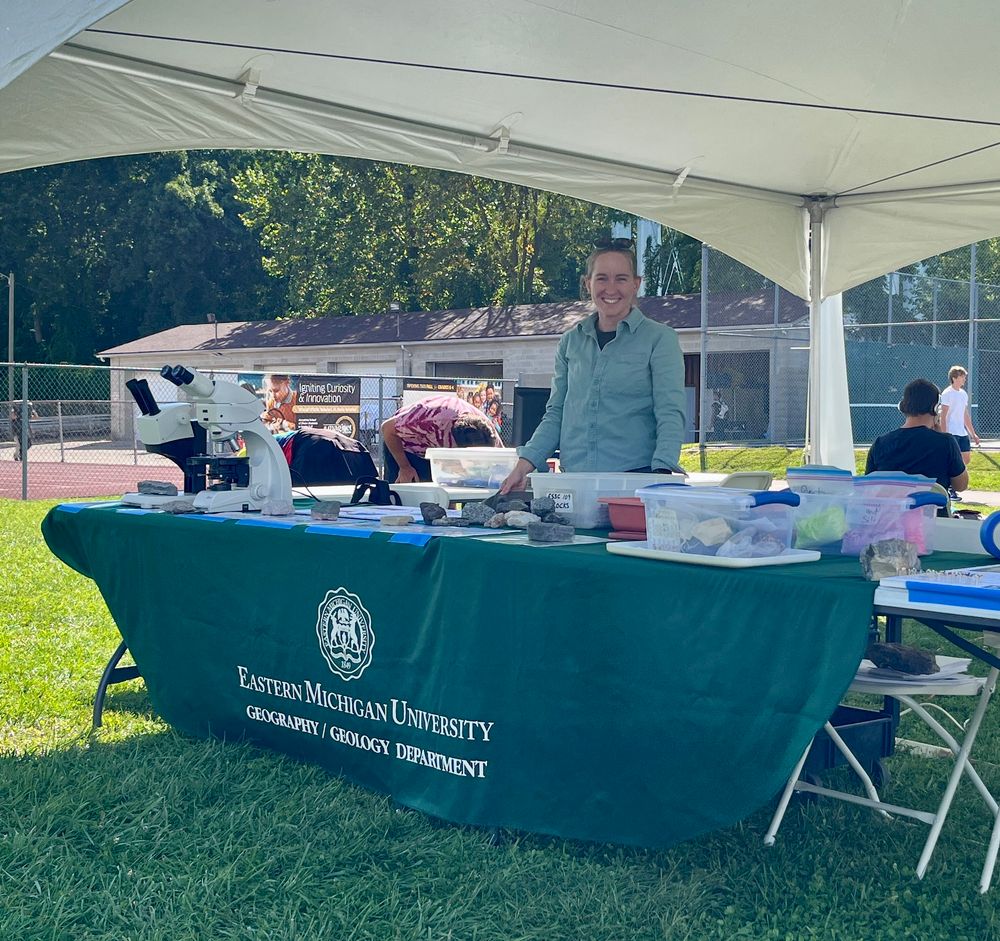 Geology professor standing behind the Eastern Michigan University booth at Ypsilanti Community High School STEM night