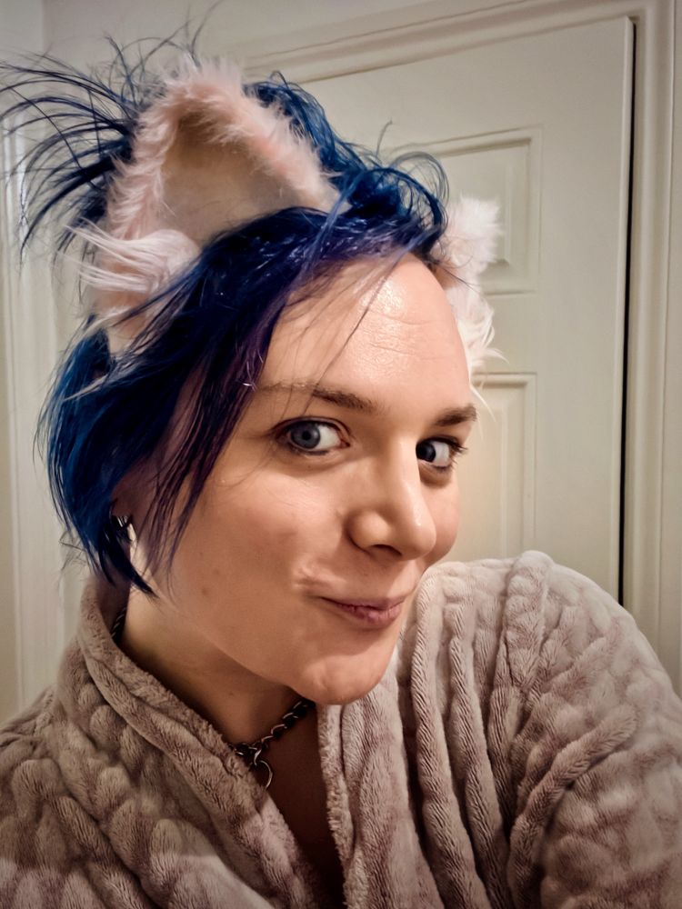 Selfie of kitty wearing a dressing gown and pink cat ears that contrast with her very blue messy hair