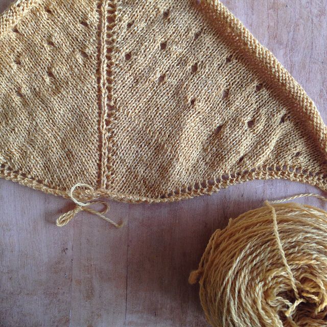 A flatlay photo of a work in progress shawl project featuring a rustic naturally dyed yellow yarn. I made this a decade ago 😳