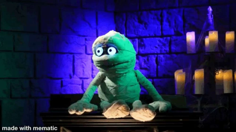 a stuffed mummy with glowing eyes is sitting on a table in a dark room .