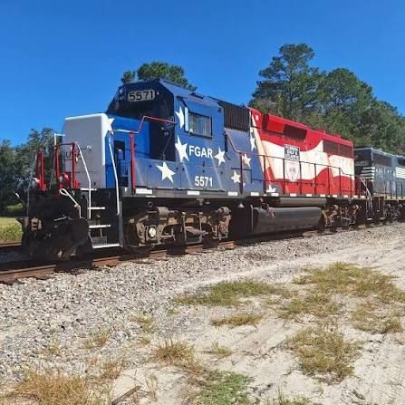 A locomotive painted like a close-up of a US flag rippling in the wind.  The front half is blue field and stars and the back half is red and white stripes.