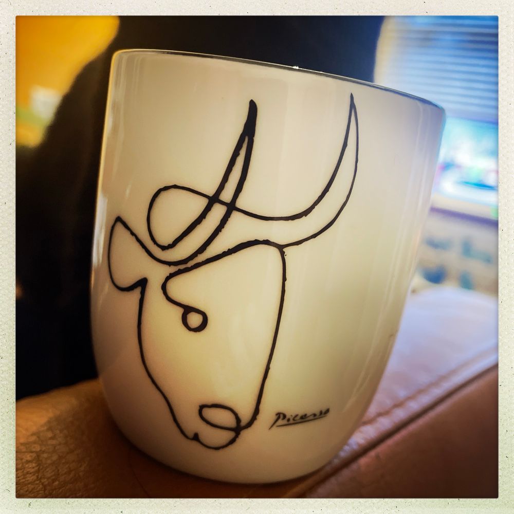 A white bone china handleless cup featuring a detail - single line illustration of a bull’s head - from Pablo Picasso’s lithograph series, Le Taureau, 1945-6.