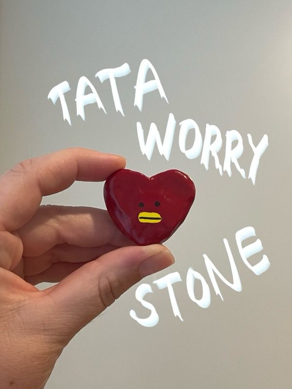 A polymer clay recreation of the BT21 character Tata (a red heart-shaped alien) as a worry stone. Text on the photo reads "Tata Worry Stone". 