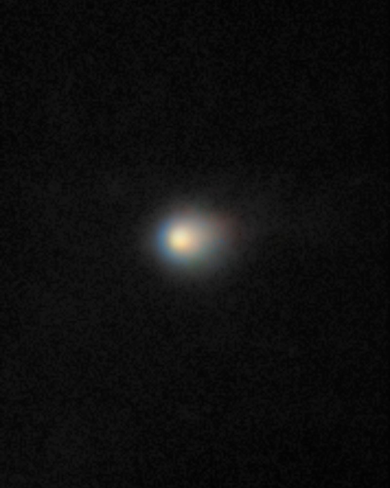 Fuzzy bright ball in the middle of a dark background. It appears to be moving to the left, as the ball is brighter on the left side.