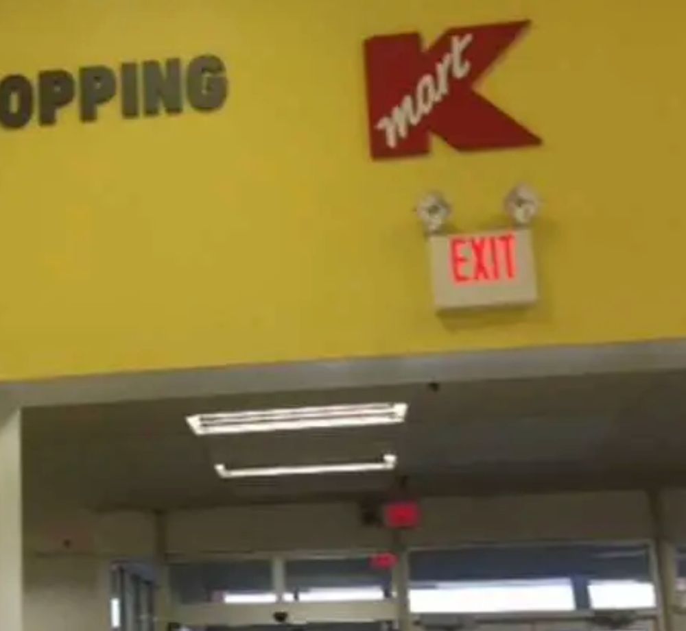 Battery-backed emergency exit light fixture over the exit of a K-Mart store