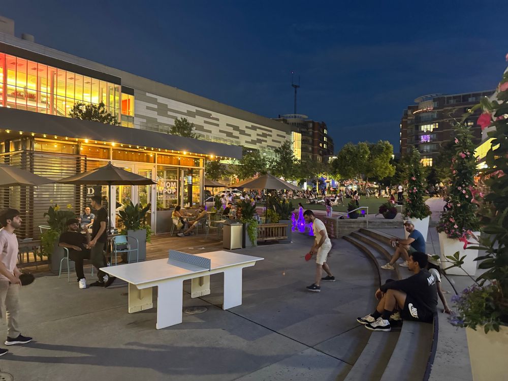 Mosaic District. Fairfax Virginia. People play outdoor ping pong, mingle on a lawn, and even sit on amphitheater style steps, by God