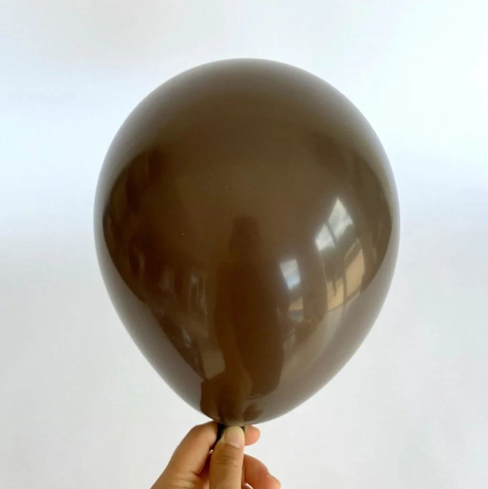 A single brown balloon held by a disembodied hand