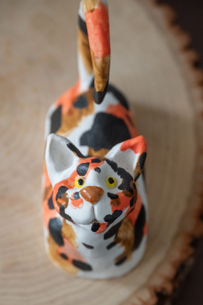 Ceramic cat figurine; POV: looking up at you.