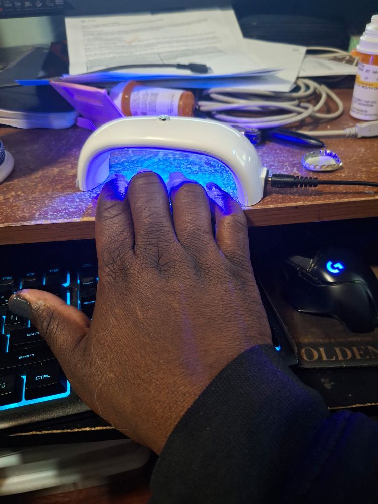 Painted fingers under a UV light atop a desk that is less messy than it looks, I promise 