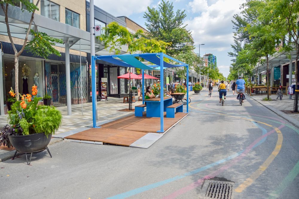Open streets with people cycling past a women siting on a patio
