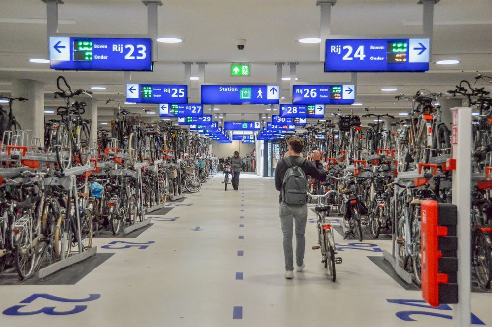 Person wheeling bike through station bike parking