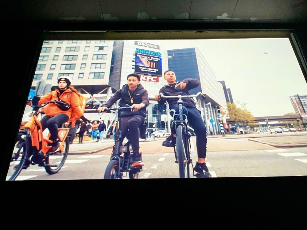 Image of a film playing on a screen of people cycling