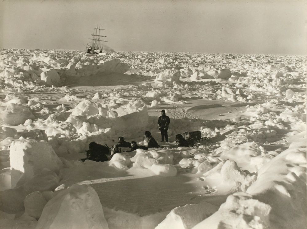 Shackleton op Antartica met op de achtergrond het schip wat vastgevroren zat in het ijs. 