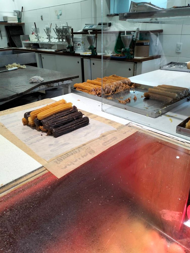 Churros on a piece of parchment paper. Some are filled with cream, others are bathed in chocolate. 
