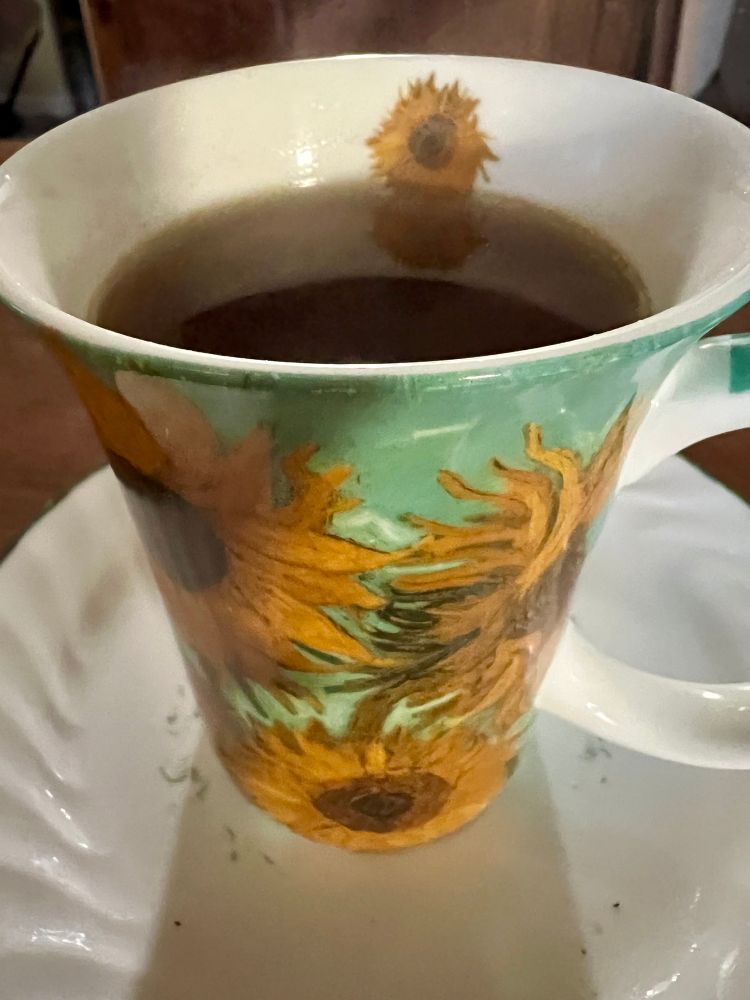 Photo of a teacup covered with images of sunflowers and filled with steaming hot pumpkin spice tea.