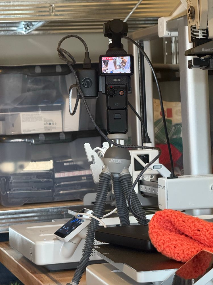 Photo of a DJI osmo pocket on a tripod in front of a Bambulabs A1 printer recording a Timelapse. The bed of the printer is obscured