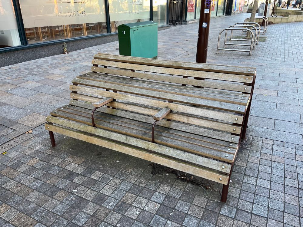 Street bench with arm rests added to prevent use by homeless sleepers