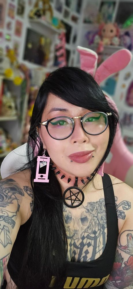 Tattooed Asian artist Merry wearing pastel pink guillotine earrings gifted by TheGuillotineProject.