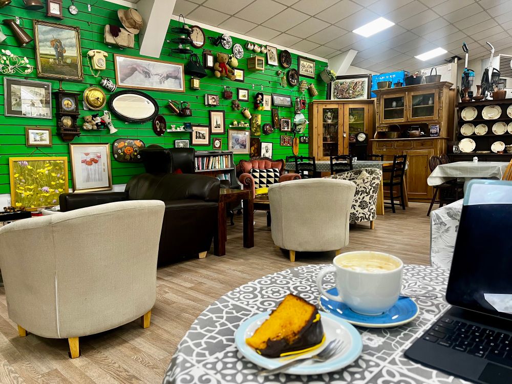 Choc and orange cake and a cap with a wall behind the table packed with antiquities and paintings 