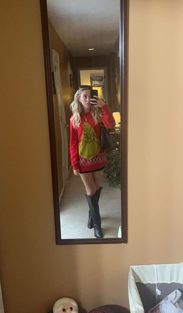 Me, a short blonde with the tip of my tongue sticking out, wearing a red sweater that hangs down past my hips and features the Grinch. I'm also wearing a pair of knee high black boots, though I'm not all that big on boots, there's a fuckton of snow out there and I know how to handle snow. 

I bet the Grinch fucks.