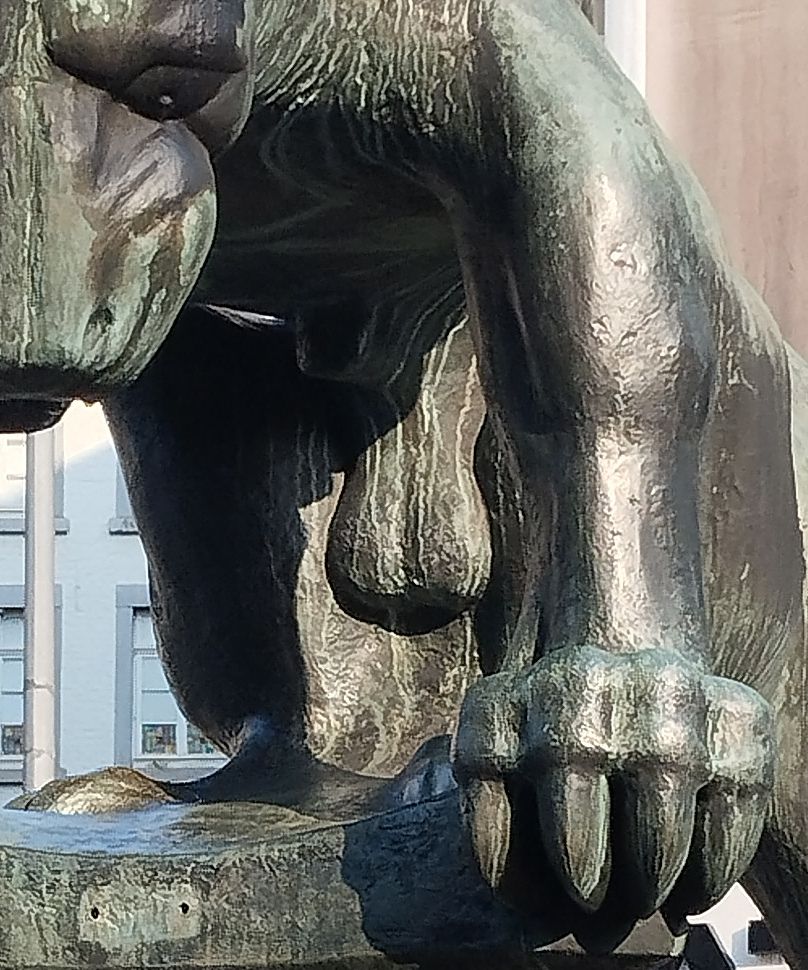 Detail of a photograph of a statue of a fantastical creature. The framing of the photograph shows the creature's muzzle and talons, but centres his genitals.