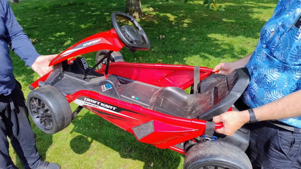 A red "Drift Kart" toy being carried by two people.