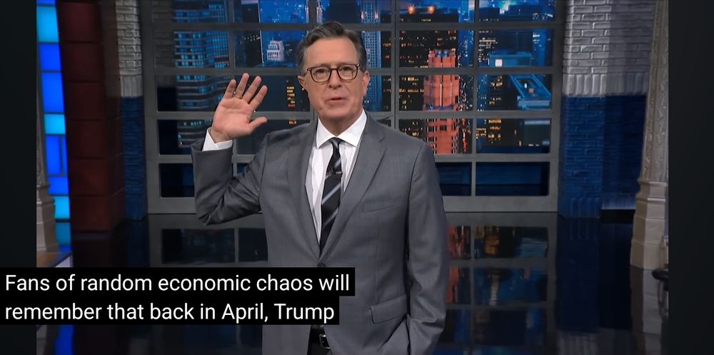 A white man in a grey suit and glasses, holds one hand up, palm toward camera.

Caption:
Fans of random economic chaos will remember that back in April, Trump