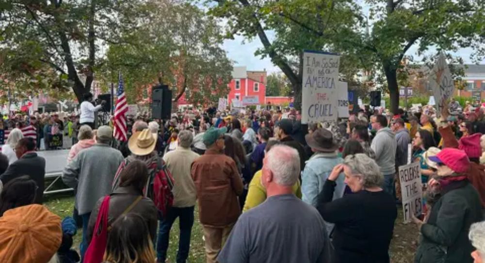 800+ people gathered at a political rally, holding signs, listening to speeches 