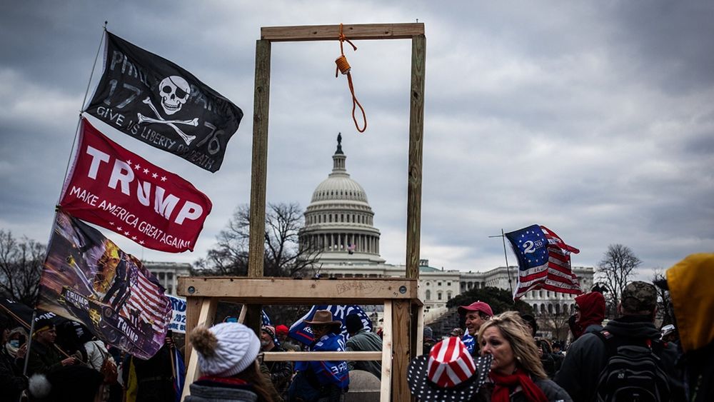 Jan 6th insurrection with a gallows and crowd of Trump supporters with Trump flags. 