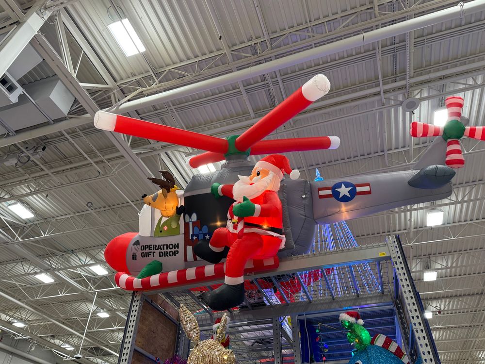 Inflatable Xmas decoration of a USAF Bell Huey with candy cane rotors and skids, a reindeer in jungle fatigues at the controls, and Santa hanging out the side door.  OPERATION GIFT DROP is stenciled under the cockpit window.