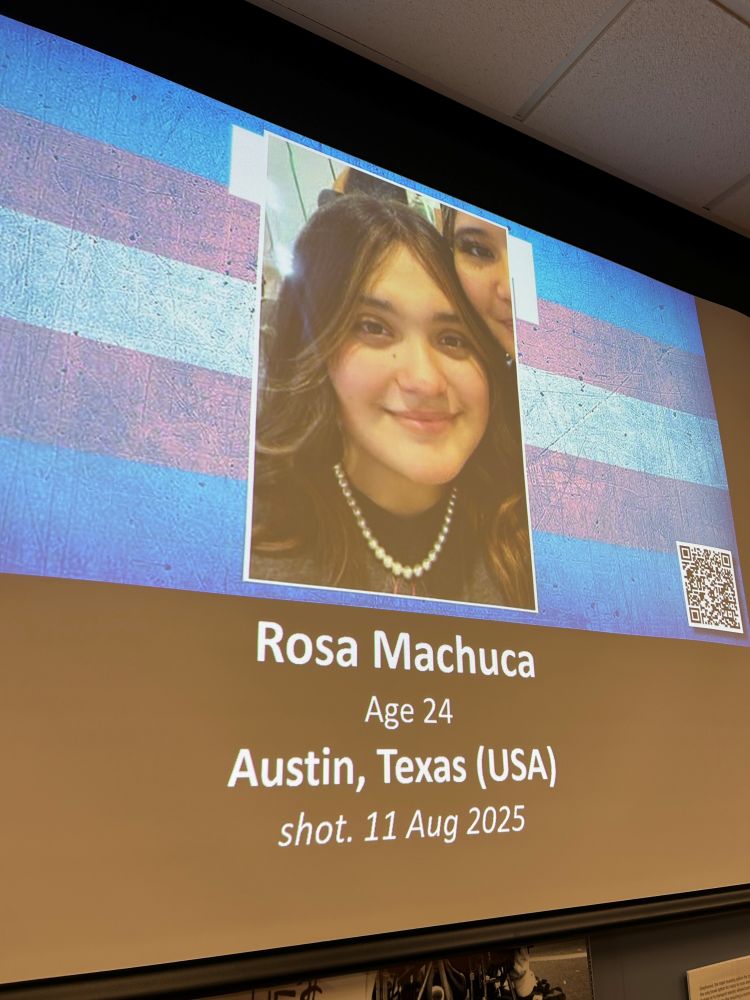 A photo of a young trans woman who was shot to death in August of 2025. She had brown hair and wore pearls. She's smiling in the photograph.