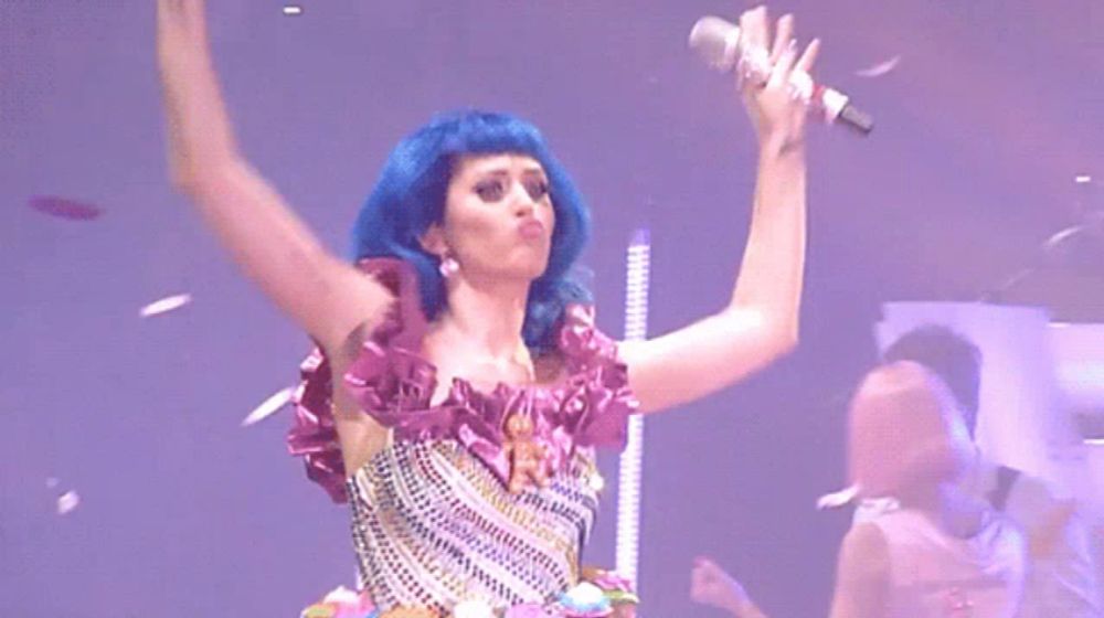 a woman with blue hair holds a microphone in her hand