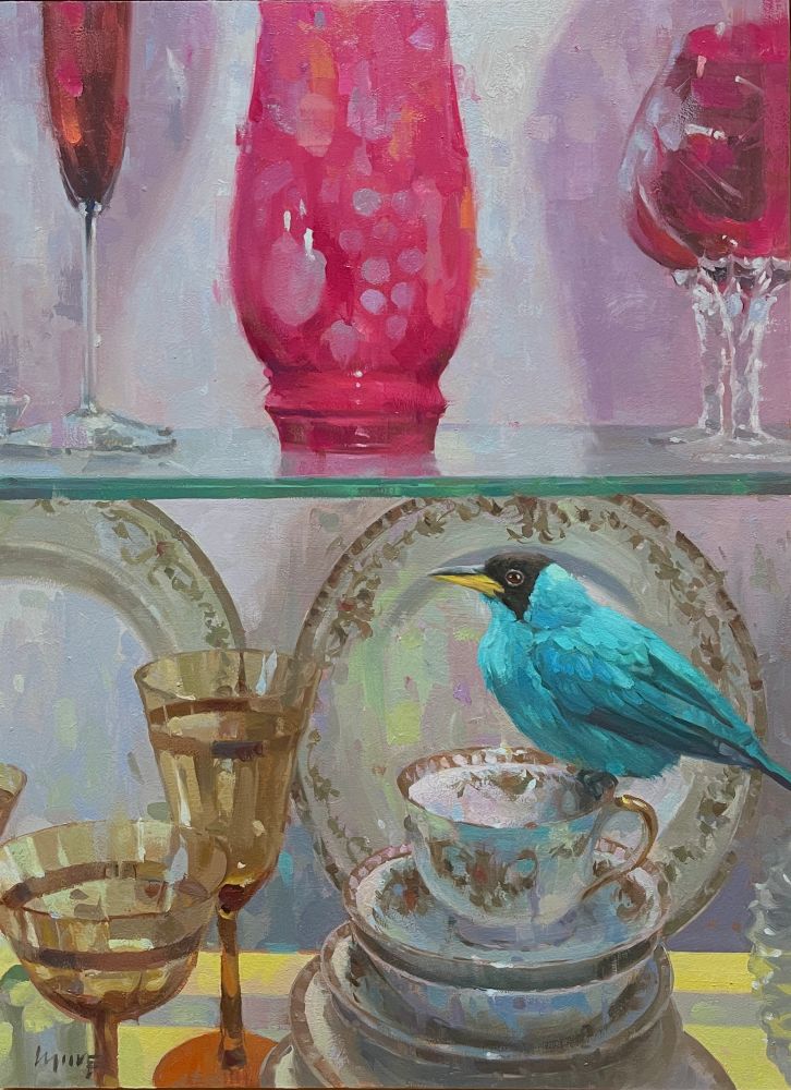 A blue bird rests on a coffee cup inside a China cupboard. 