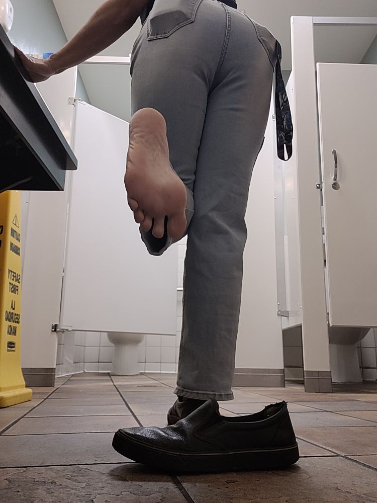 Me turned away from the camera with my foot out of sock and show. Sole facing you