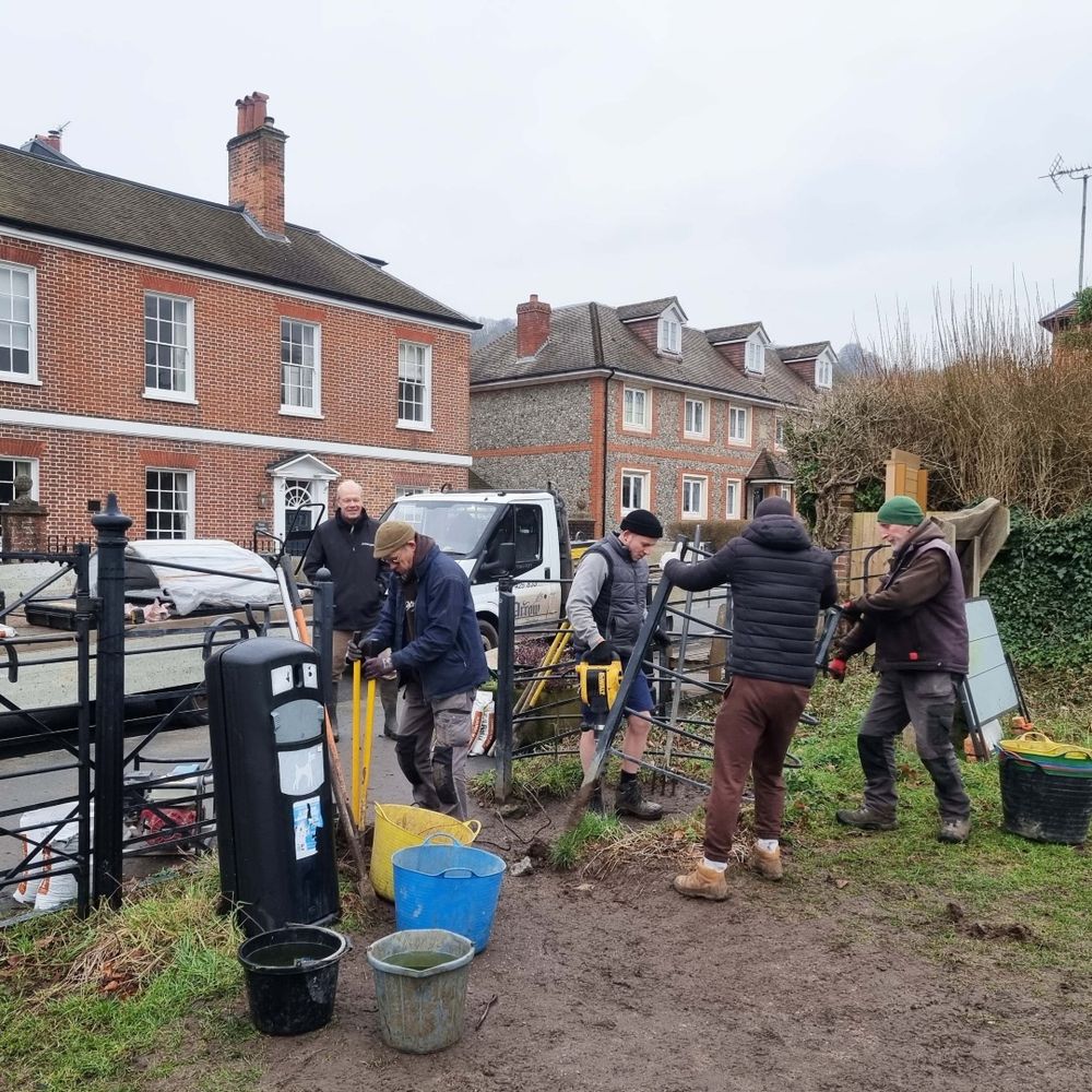 A group of men installing a new gate at the entrance to a field.