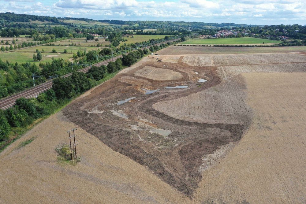 Aerial photo of a field with a large area dug out with small ponds forming inside.