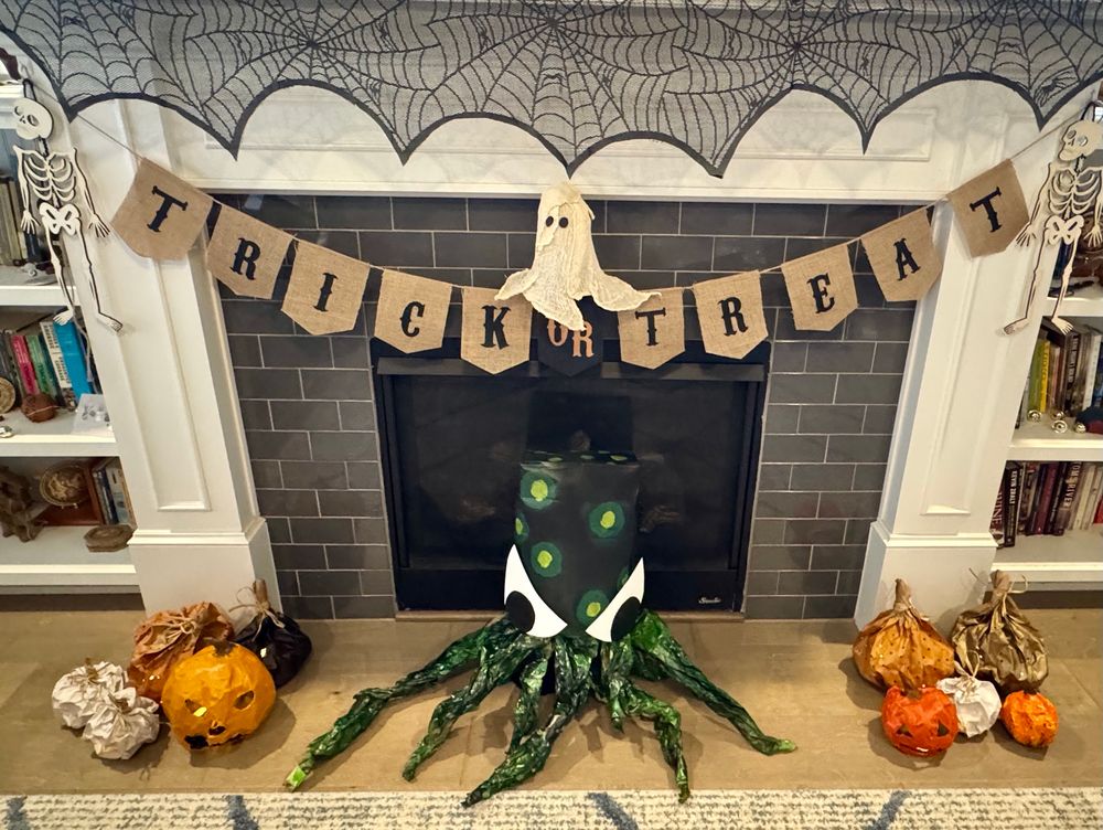 A green and black kraken with giant eyes, glowing spots, and crinkly tentacles made of paper and paint