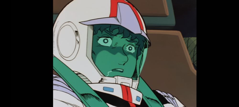 Cena de MS Gundam. Close no Amuro Ray usando roupa espacial branca, capacete com visor transparente, dentro do Gundam. Ele está com o olho parado estatelado com a boca aberta babando totalmente fora do ar