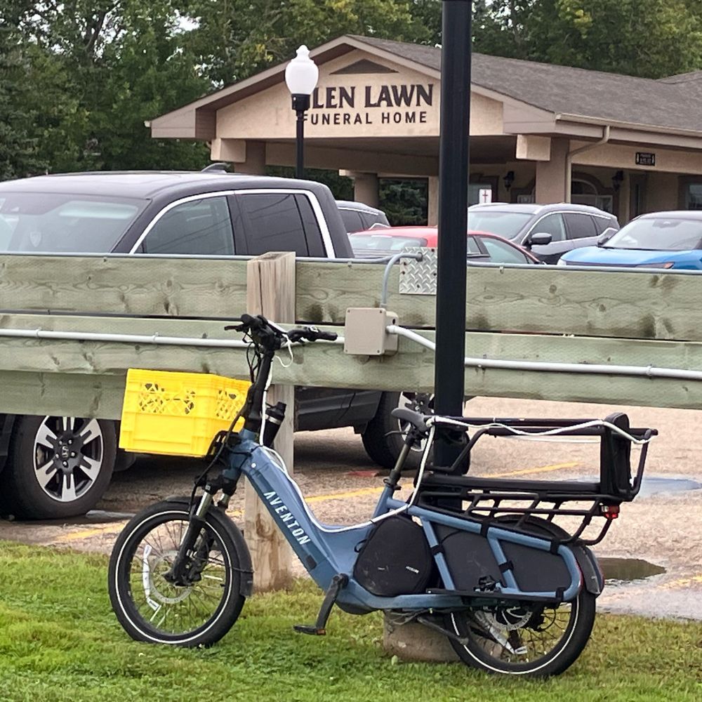 A blue ebike chained to a light post in front of a funeral home.