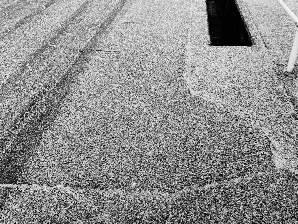 少しだけ雪の積もったアスファルトの写真