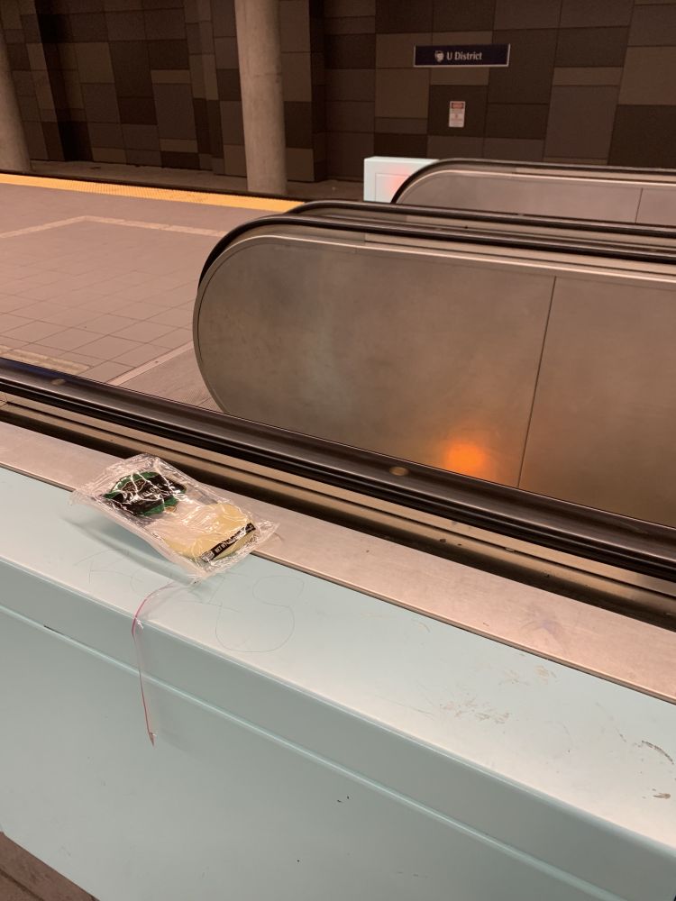 an escalator at the Capitol Hill light rail station with an opened package of provolone cheese next to the moving handrail