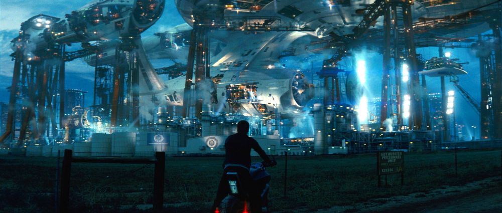Kirk on a space motorcycle back to camera looking at the giant USS Enterprise under construction on the ground for some reason.