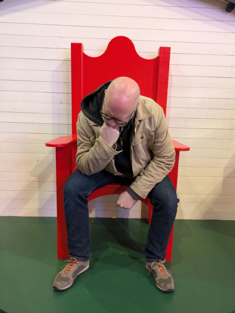 A very sad man, sitting in a red chair 