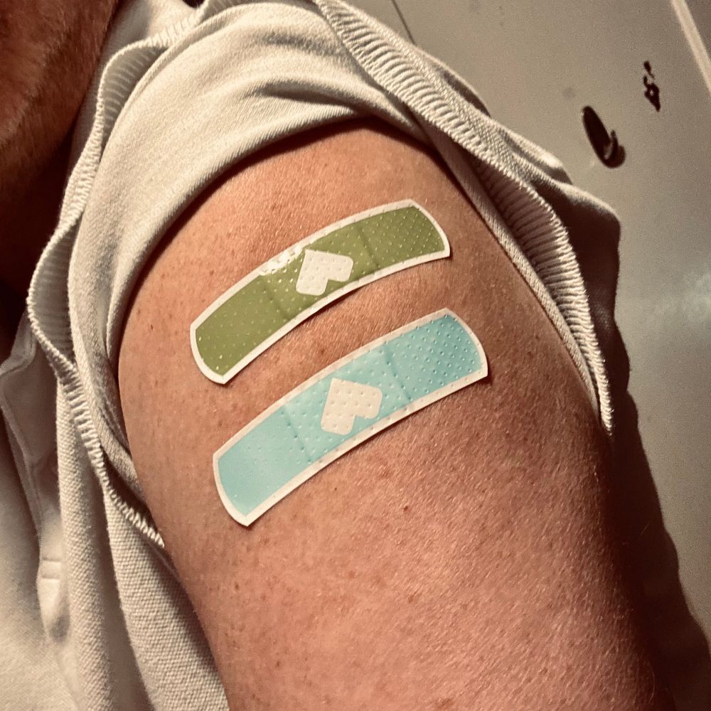 Two bandages on the upper arm: green and blue, with hearts. 