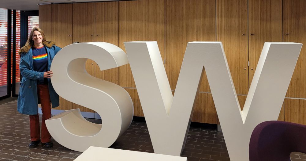 Person standing next to large letters S and W